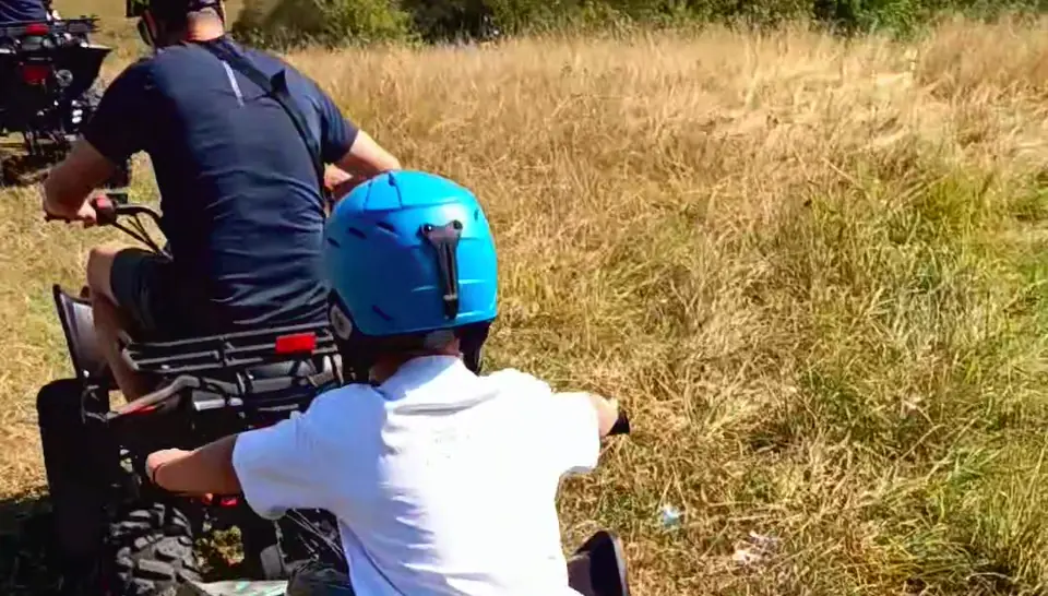 Copil cu cască albastră pe un ATV, pe o pajiște din jurul Cisnădiei